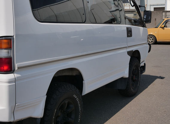 Side view of a 1994 Mitsubishi Delica 4WD diesel van with lifted aftermarket suspension, rugged off-road stance, and white two-tone paint – ideal for overlanding or adventure travel.