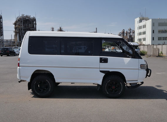 Side view of a 1994 Mitsubishi Delica 4WD diesel van with lifted aftermarket suspension, rugged off-road stance, and white two-tone paint – ideal for overlanding or adventure travel.