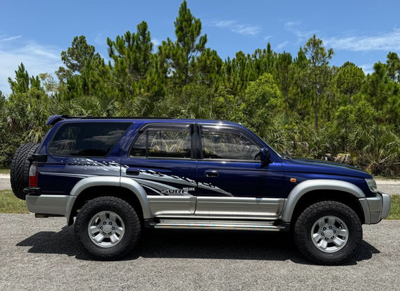 Driver side profile of 1996 Toyota Hilux Surf SSR-G showing original Surf side graphics, factory alloy wheels and 4WD