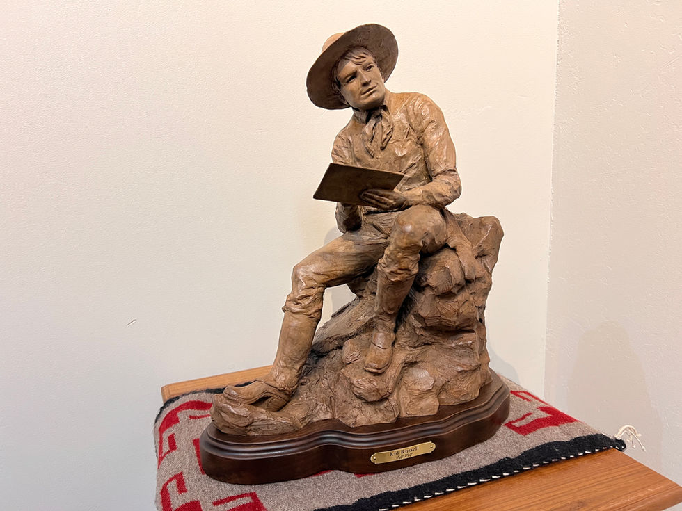 a statue of a young Charlie Russell sitting on a rock reading a book, bronze sculpture, gold river gallery