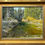 Thumbnail: painting of a river surrounded by green trees with snowy tips in a gold frame by Craig fetzer