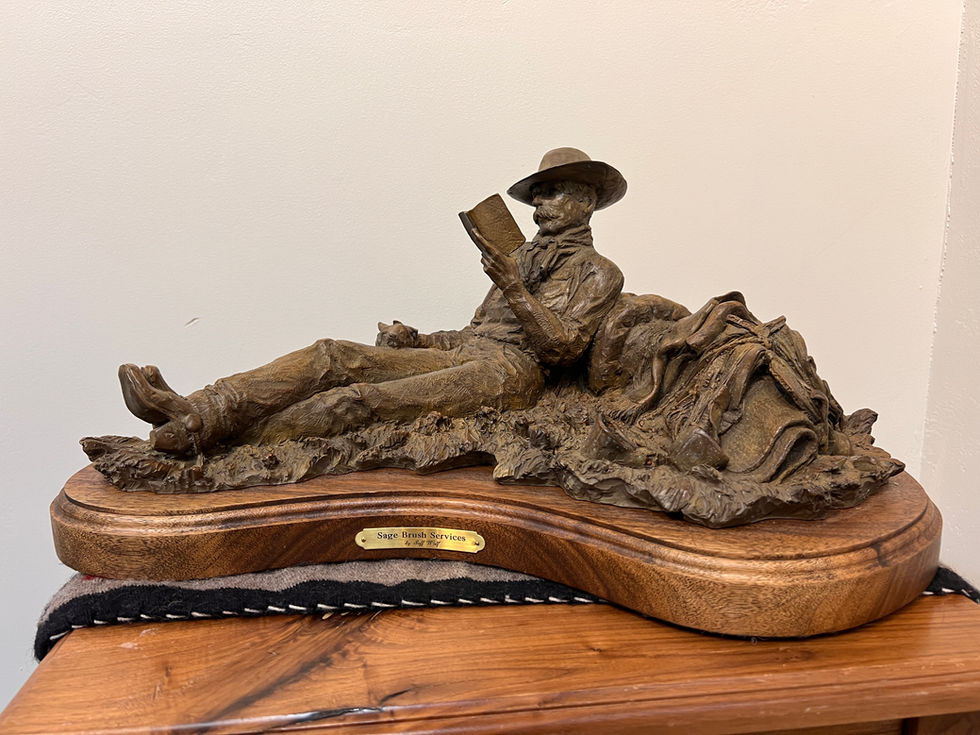 a statue of a man laying down reading a book with his dog, gold river gallery, bronze sculpture