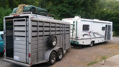 Silver stock trailer parked next to a white camper RV.