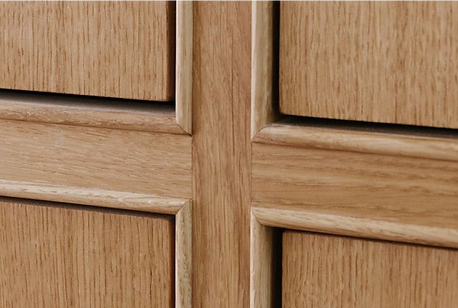 A wooden cabinet panel with natural finish and raised cross-shaped trim.
