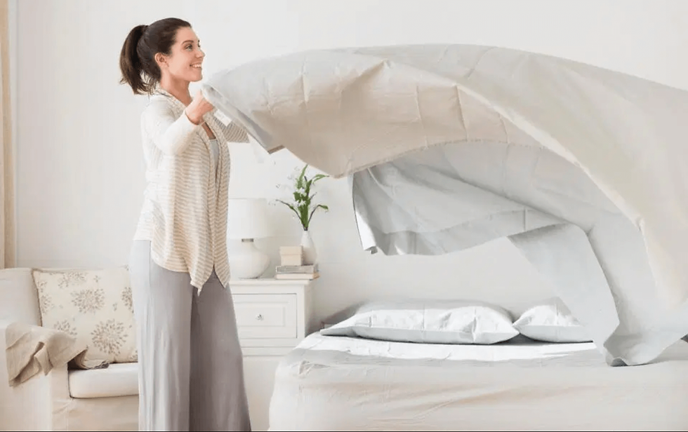 Woman fluffing her bedsheets and making the bed