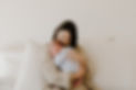 This is a picture of a mother holding her newborn baby on her bed. They are snuggling together as they pose during a newborn photography session in Bend, Oregon.