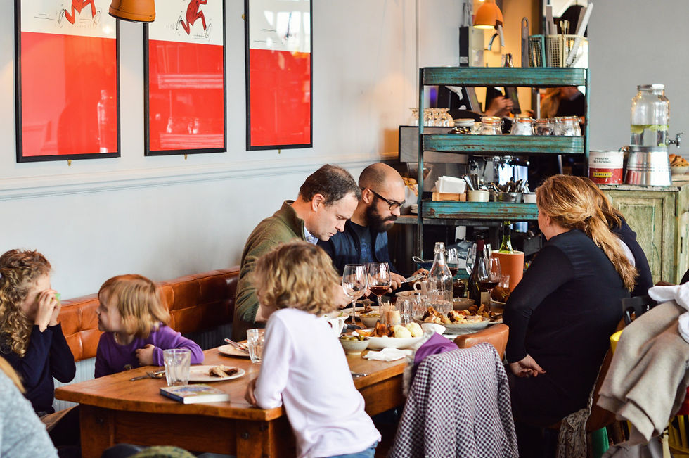 Wide-angle view of a cosy London pub dining room with families eating Sunday lunch