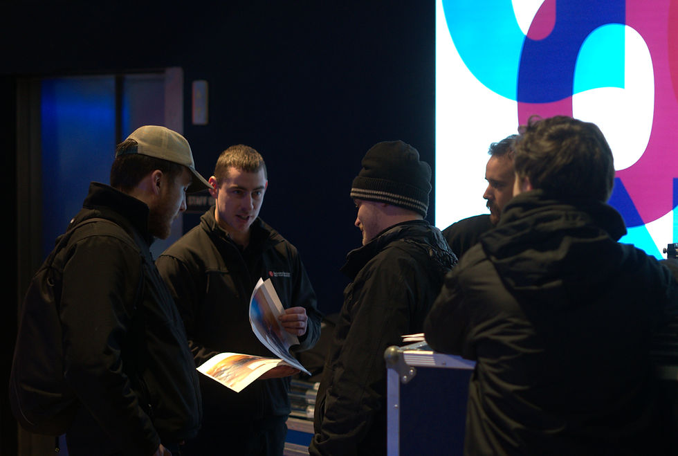 People gathered around a table looking at a paper event plan, discussing how to improve its structure.