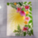 Embossed floral card with pink and orange flowers, green leaves, and a yellow sunburst pattern on a gridded work surface