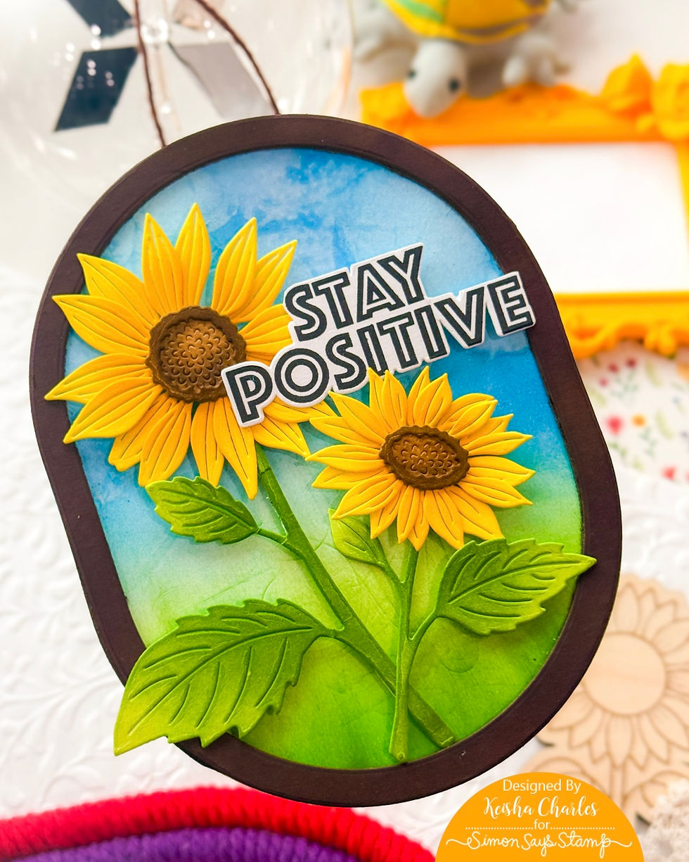 Handmade sunflower card with STAY POSITIVE text on a blue-green background and dark brown border, bright and cheerful.
