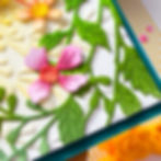 Embossed floral card with pink and yellow flowers, green vines and leaves on white, with teal and striped edges.