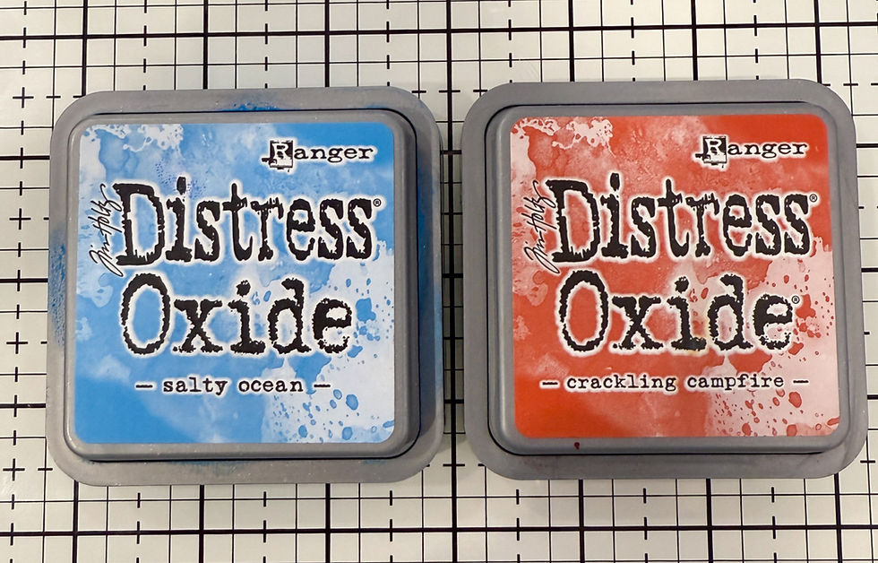 Two Distress Oxide ink pads labeled "salty ocean" in blue and "crackling campfire" in red, on a black-and-white grid background.