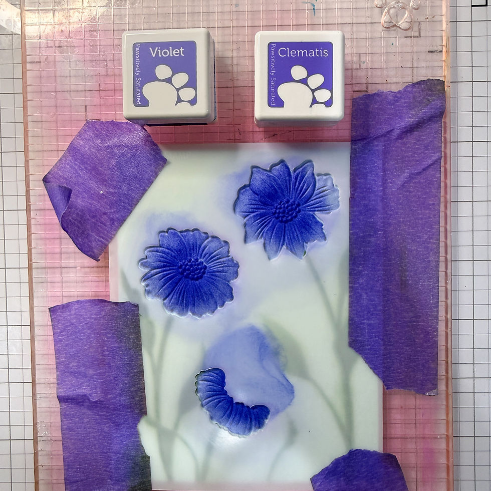 Purple inked floral stamp test on gridded craft mat, with Violet and Clematis ink pads and blue flower impressions.