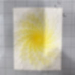 Abstract yellow-and-white radial teardrop pattern on paper over a gray grid background, like a sunburst or flower-like design