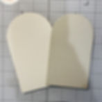 Two overlapping cream-colored paper cutouts on graph paper, creating a simple craft layout with no text visible