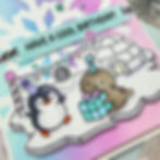 Cute penguin and seal celebrate a birthday on ice with party hats, gift, and banner. Background is pastel purple and blue. Text: Have a cool birthday!