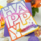 Colorful "HAPPY" card with an ombre design placed against a purple background. A banner reads "HAPPY BIRTHDAY." Bright and cheerful.