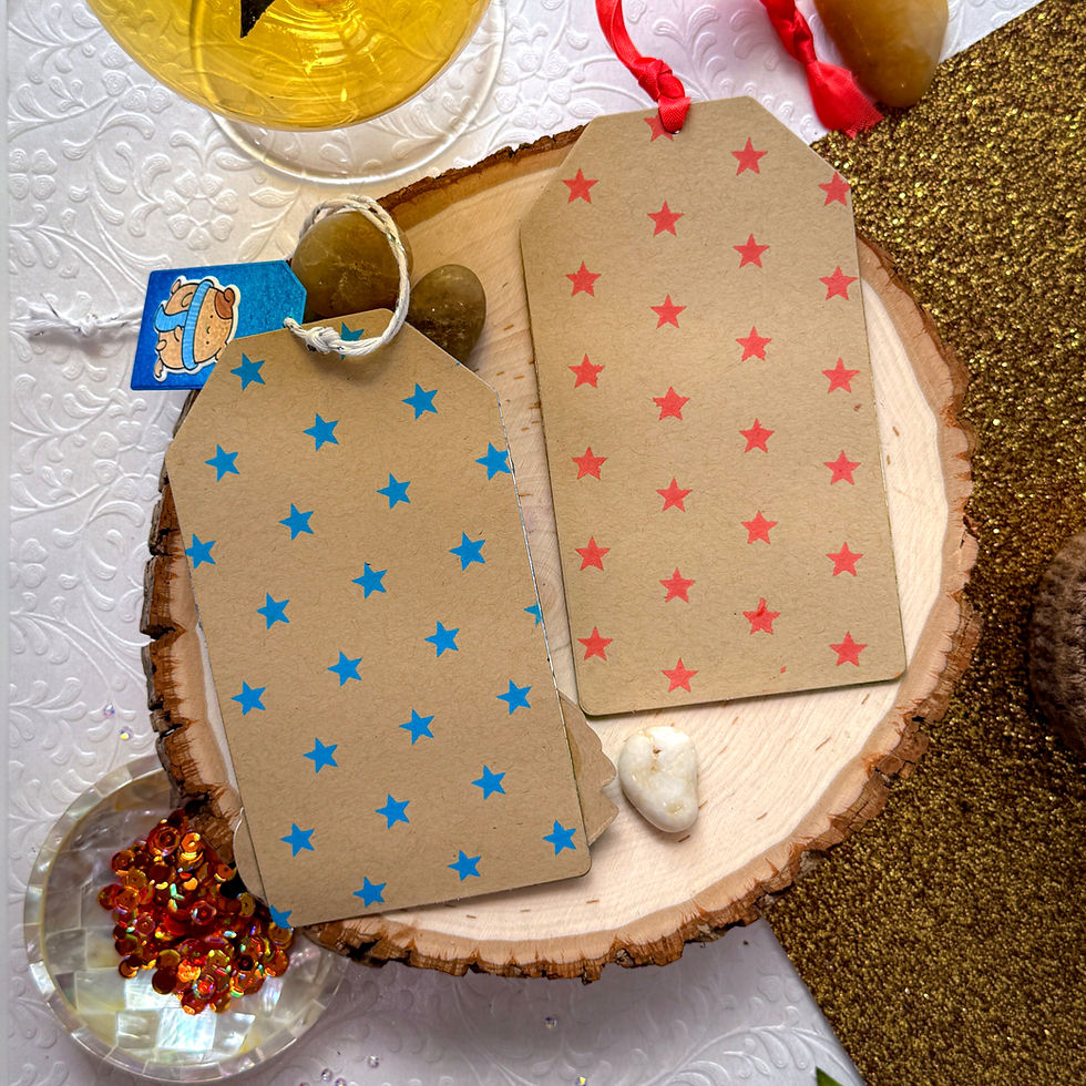 Star-patterned gift tags on wood; one with blue stars and twine, the other with red stars and ribbon. White textured background.