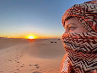 Sabi watching sunrise over Sahara Desert dunes.