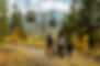 Family of four hikes under The Breckenridge Gondola. Yellow fall foliage and mountains in background.  