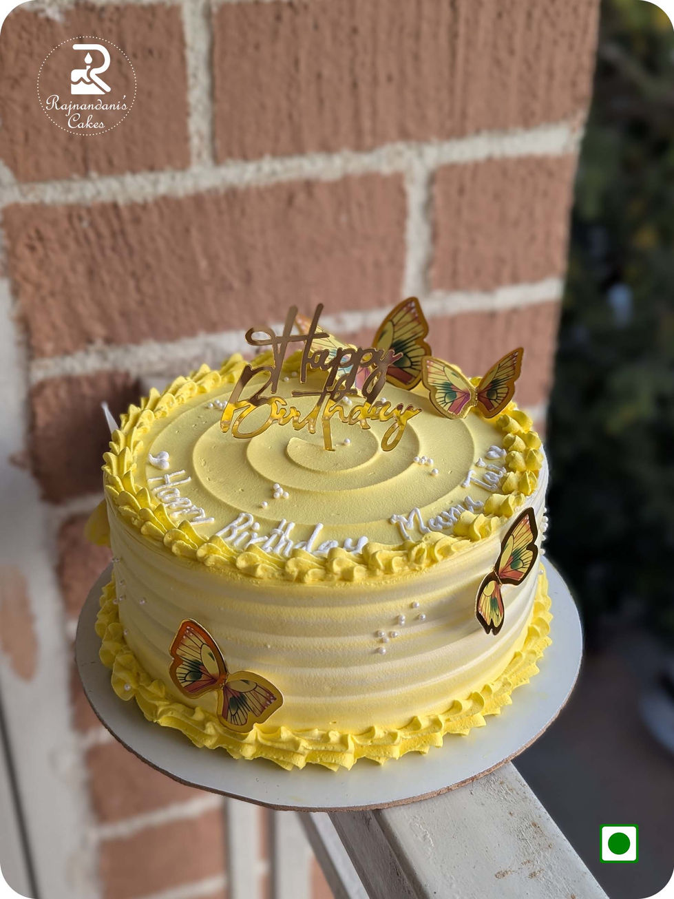 Bright yellow whipped cream birthday cake with textured ridges, butterfly accents, white pearls, and gold cake topper.