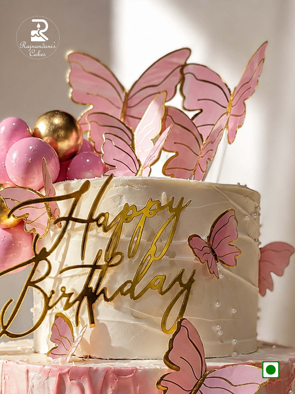 Two-tier pink and white birthday cake adorned with flutter butterflies, gold and pink spheres, and acrylic topper.