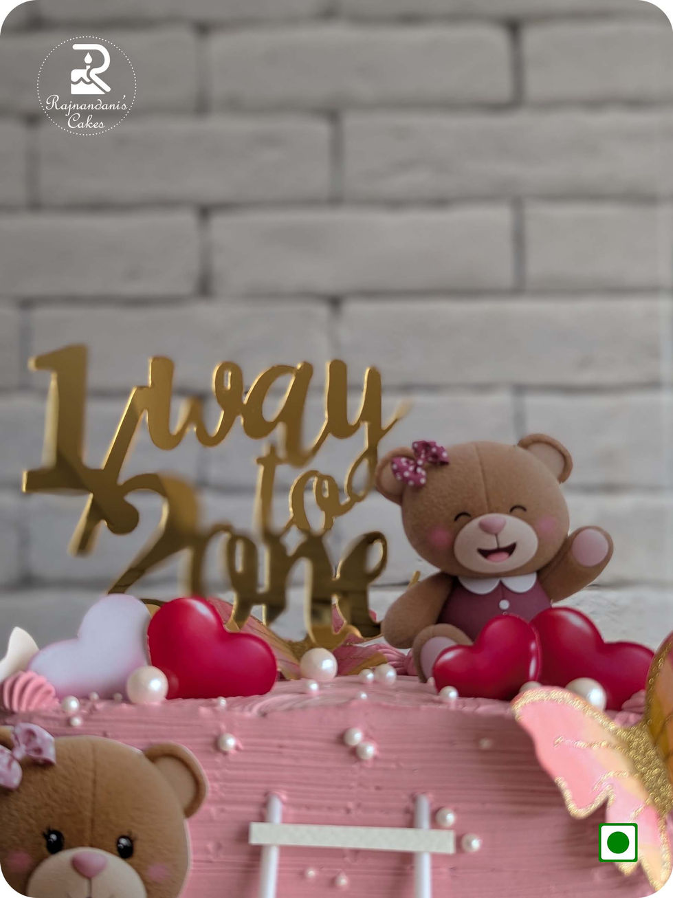 100% eggless pink half birthday cake by Rajnandani Cakes frosted in textured fresh whipping cream, topped with a golden 1/2 W