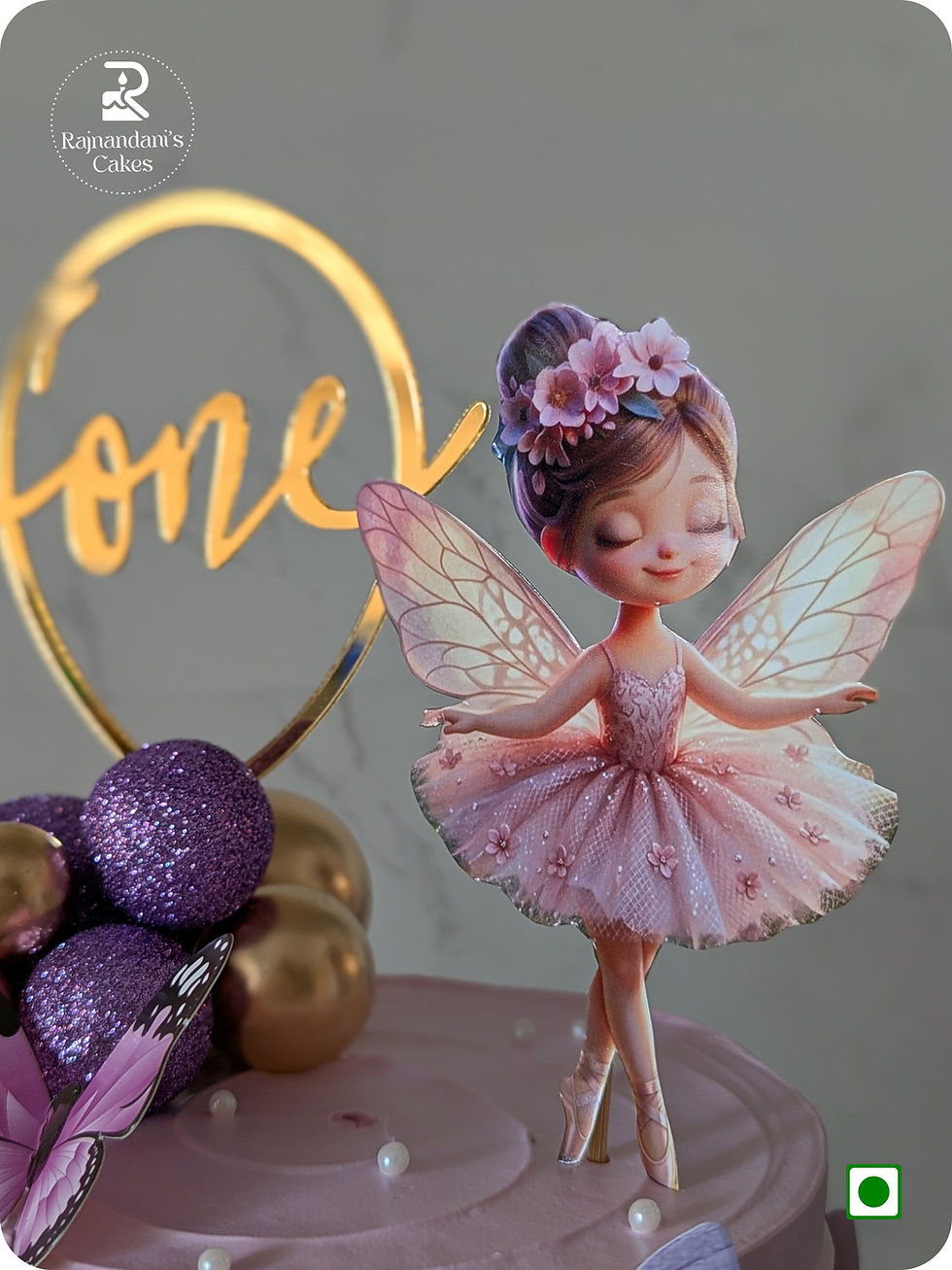 Two tier pastel pink and lavender fairy cake decorated with butterflies, spheres, and ballerina by Rajnandani's Cakes.