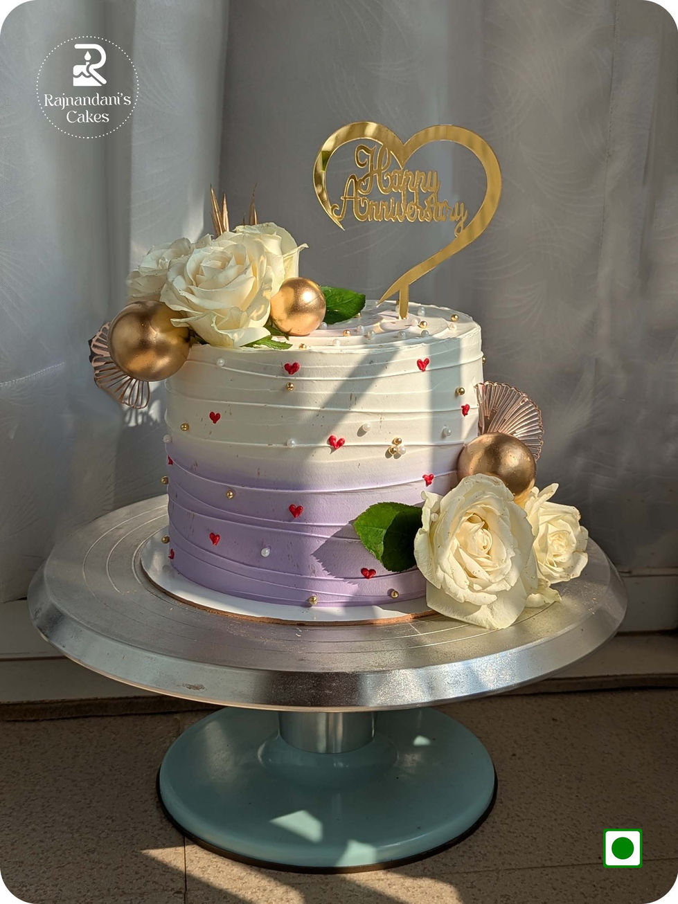 Lavender ombre textured cake accented with cream roses, metallic spheres, and heart details by Rajnandani's Cakes.
