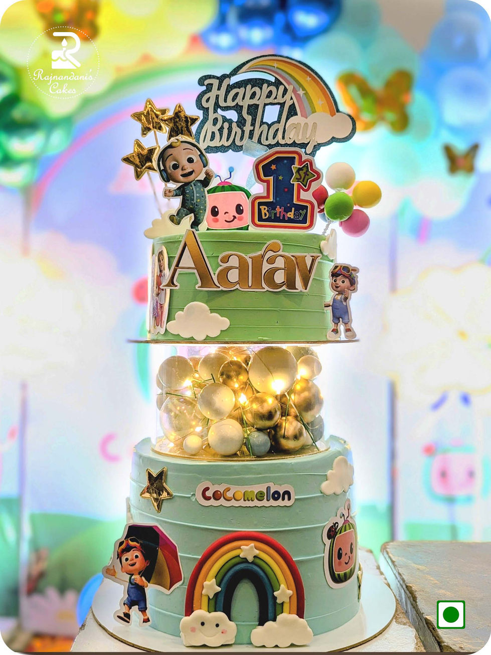 Three Tier Cocomelon cake featuring illuminated separator with golden spheres by Rajnandani's Cakes.