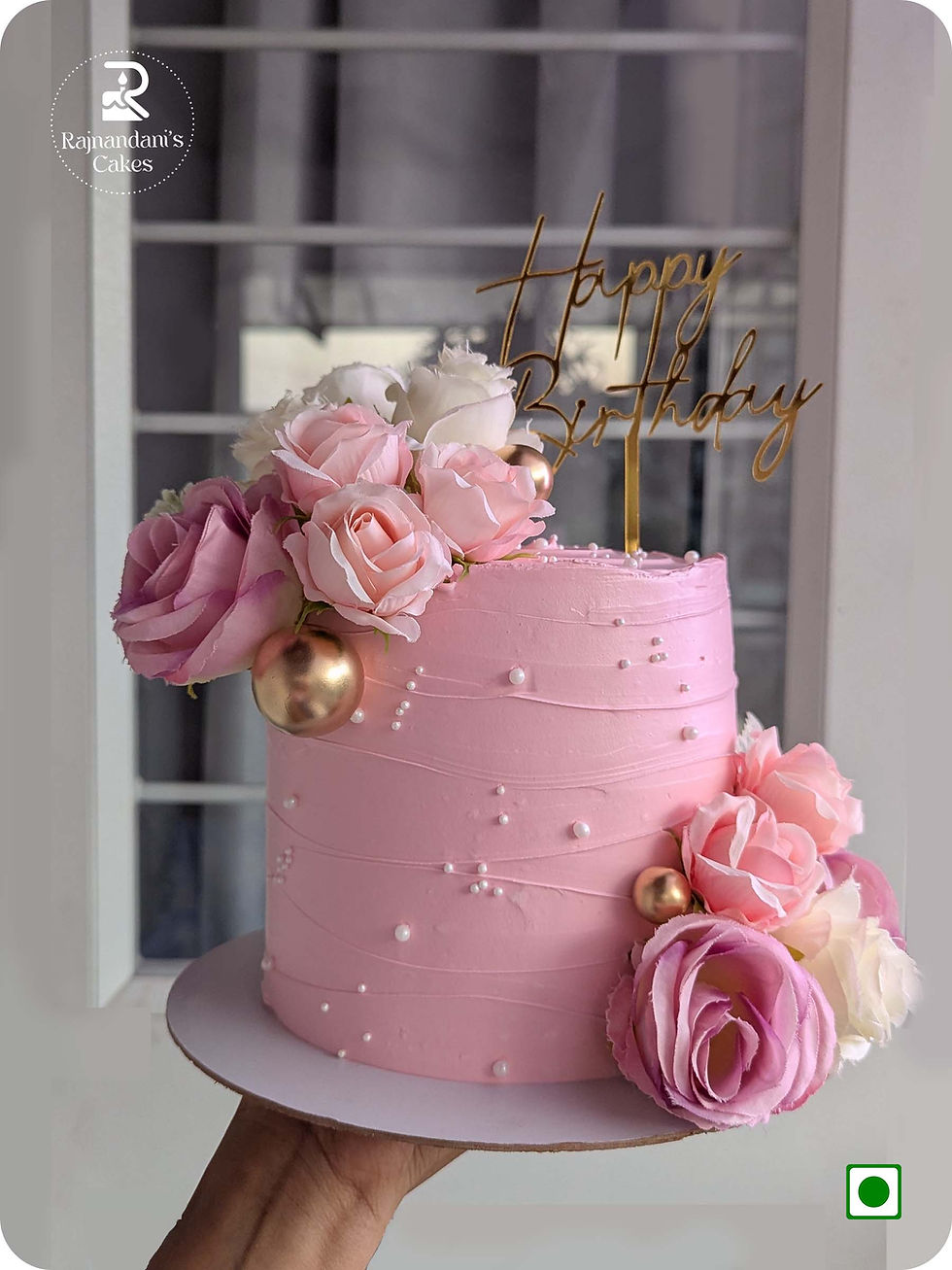 Tall pink textured cake decorated with fresh roses, metallic spheres, and edible pearls by Rajnandani's Cakes.
