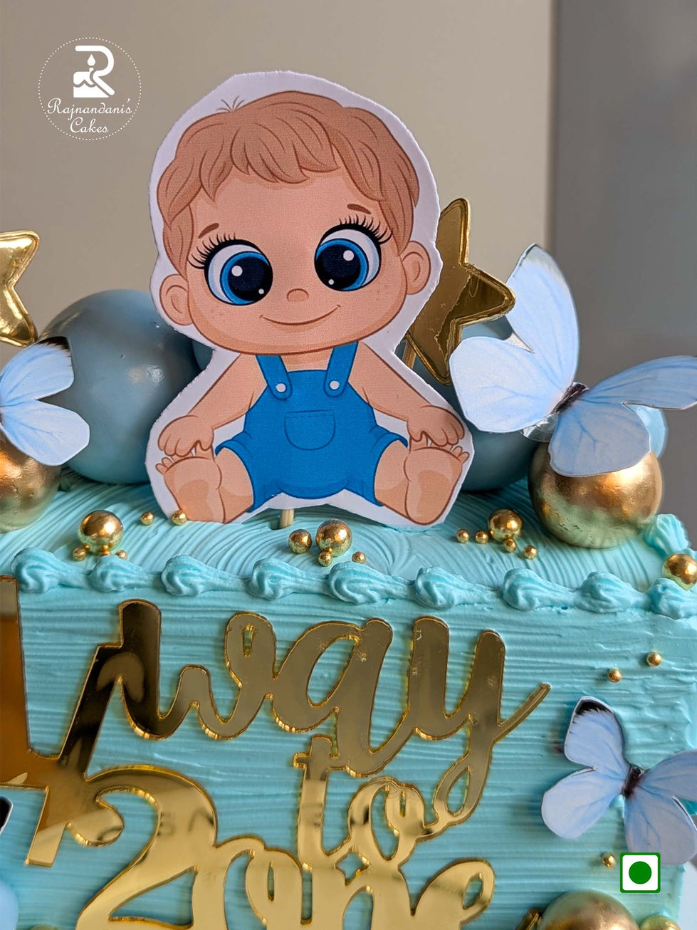 Blue 1/2 way to one half birthday cake with baby topper, gold spheres, and butterflies by Rajnandani Cakes in Pune
