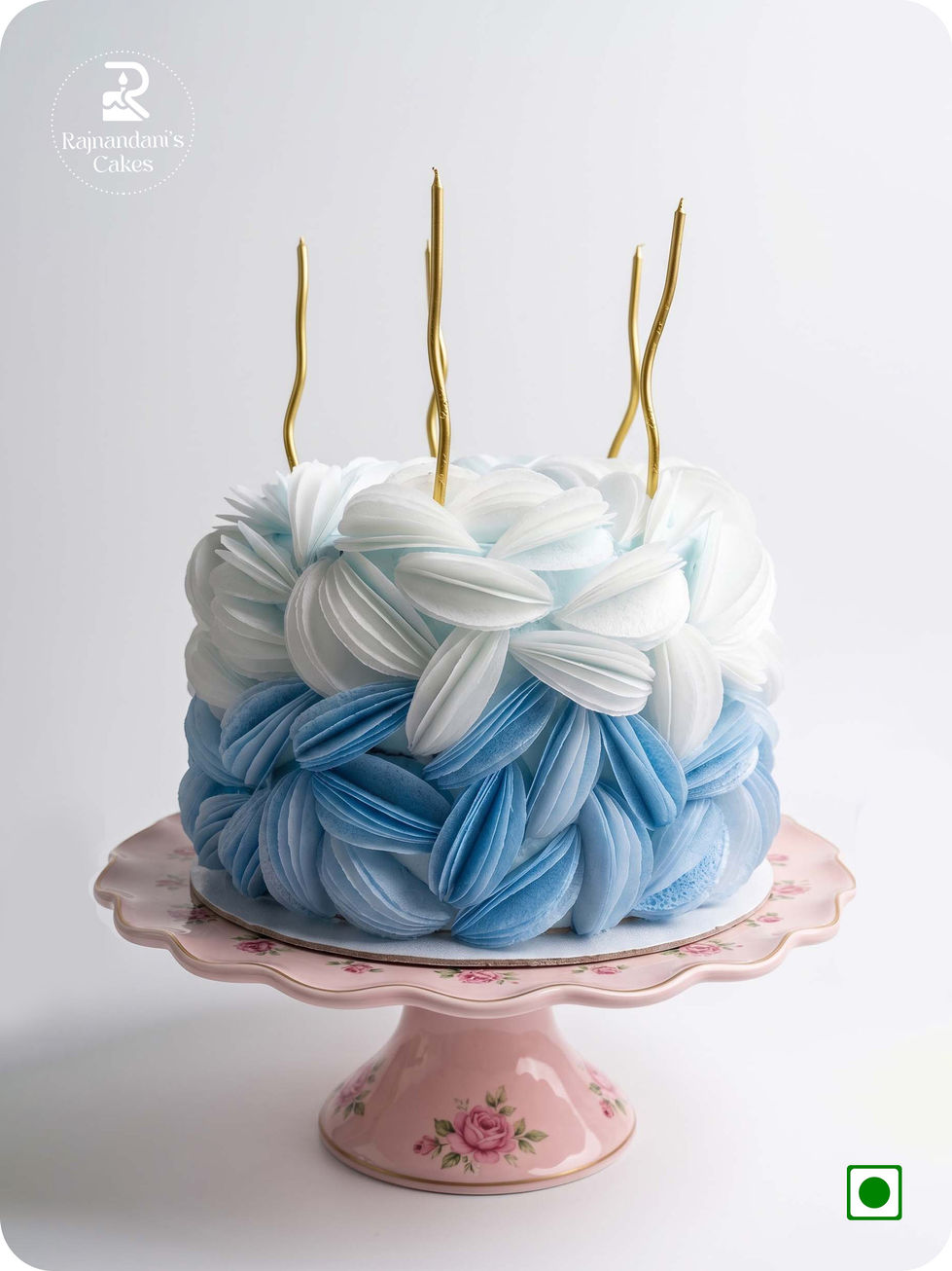 blue and white ombre cake sculpted with edible delicate wafer paper petals and metallic candles by Rajnandani's Cakes.