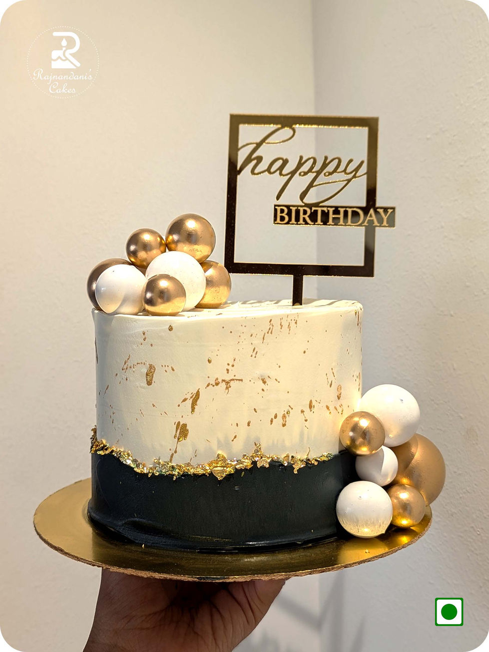 Single-tier black and white modern birthday cake decorated with gold leaf accents, gold splatters, metallic gold and white