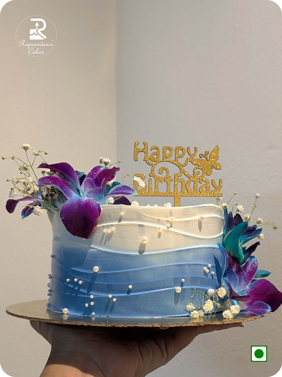 Blue and white ombre textured Whipping cake garnished with fresh purple-blue orchids, baby's breath, edible pearls, and a