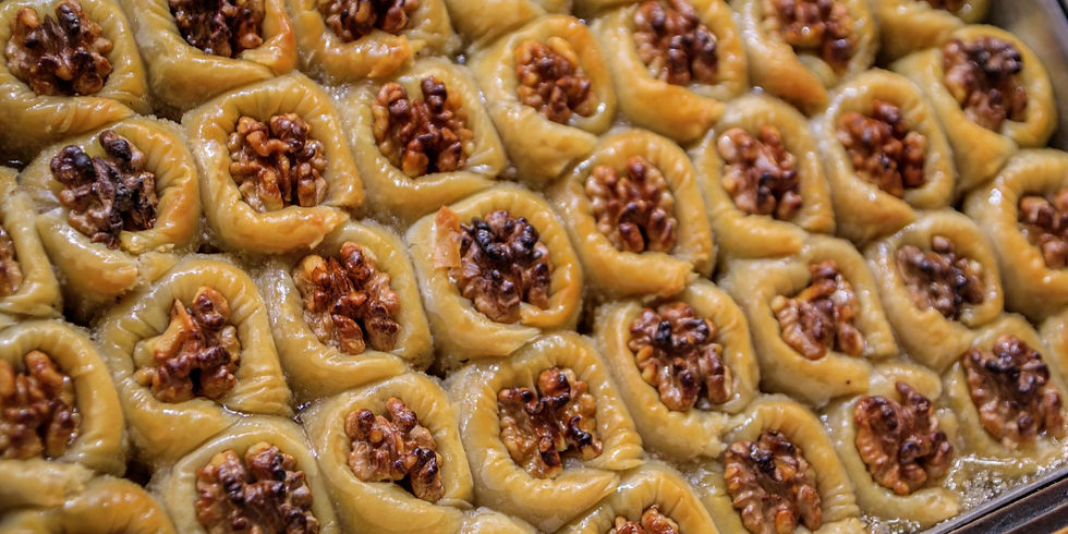 Bagværk af sukkerlagebagte baklava med valnøddefyld. Gyldenbrun farve og skinnende overflade i et bageark. Ingen tekst.