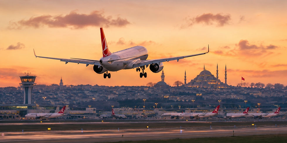 Fly på vej til landing ved solnedgang i en lufthavn, med byens skyline og en smukt oplyst moské i baggrunden.