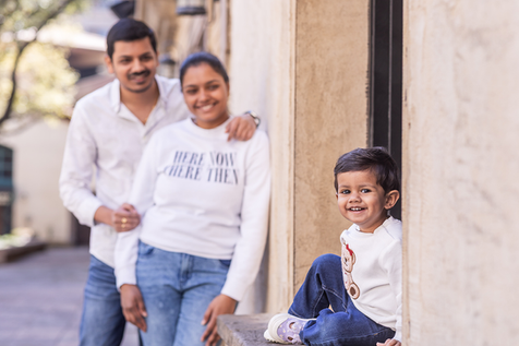 Family photo parents on the background looking on the baby smiling to camera.