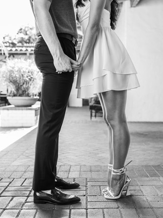  A black and white photo focusing on the lower half of a couple holding hands, showcasing their connection and style.