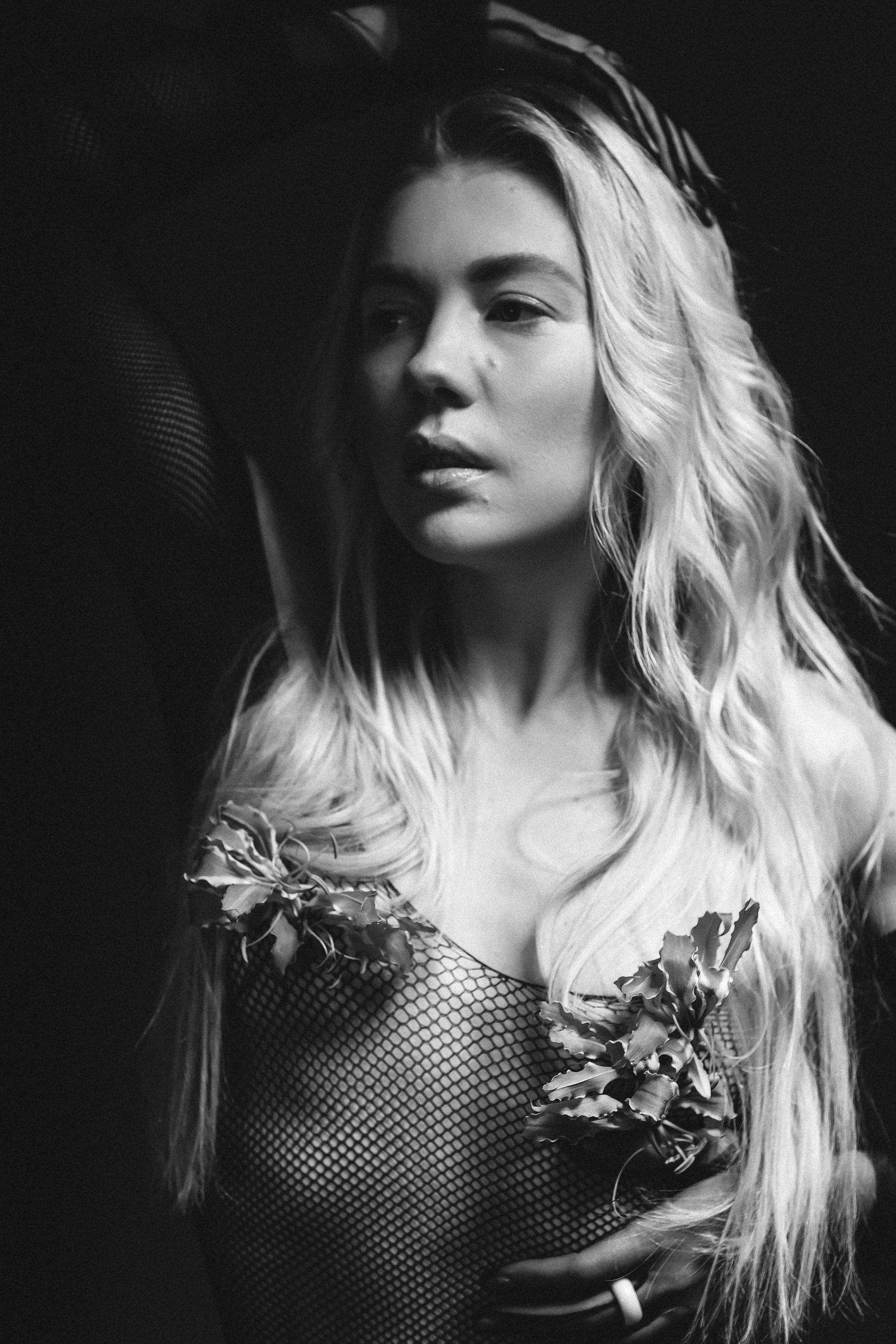 Black and white portrait with dramatic lighting and fishnet detailing.