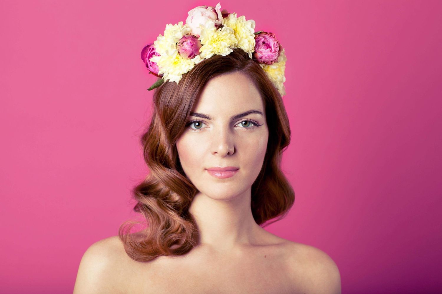 Romantic portrait with yellow and pink flower crown against pink background.