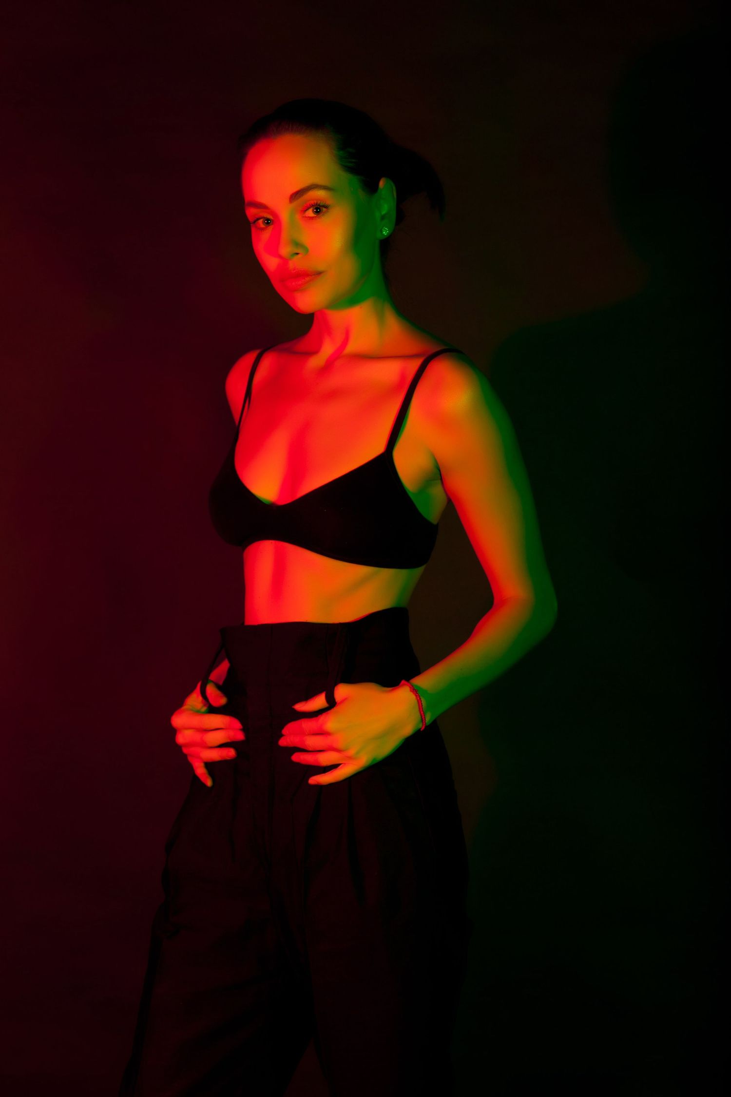 Dramatic portrait with red and green lighting effects on dark background.