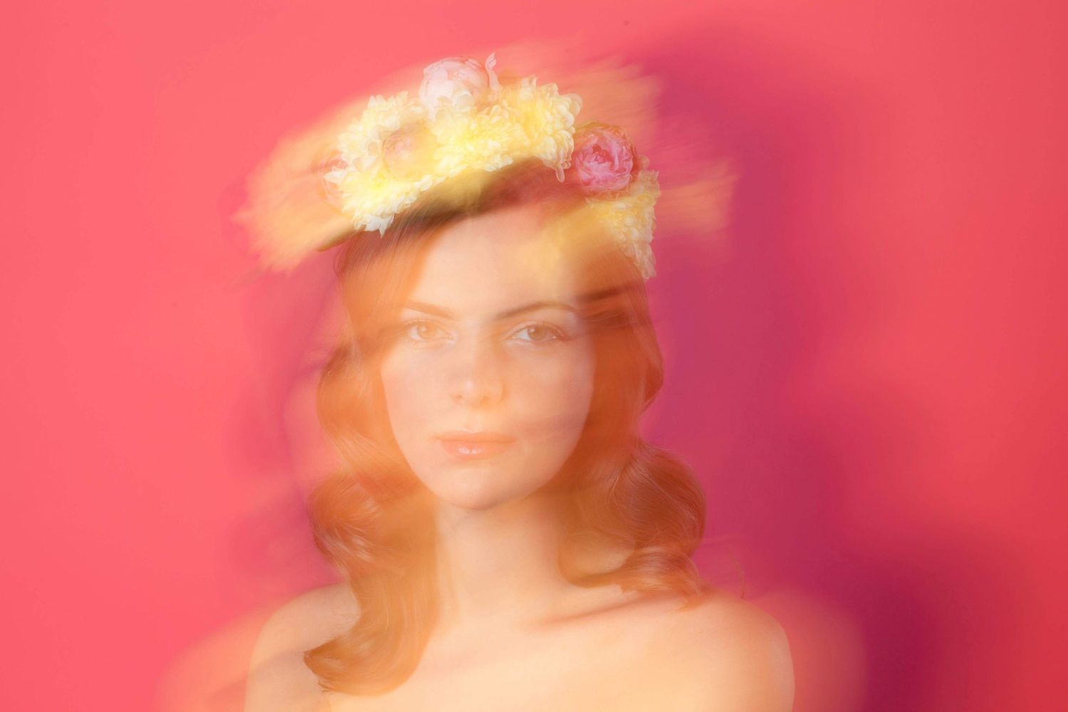 Dreamy portrait with motion blur and golden crown effect against pink backdrop.