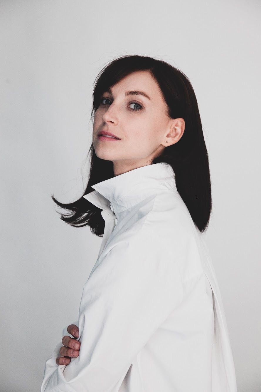 Clean studio portrait in white collared shirt against light background.
