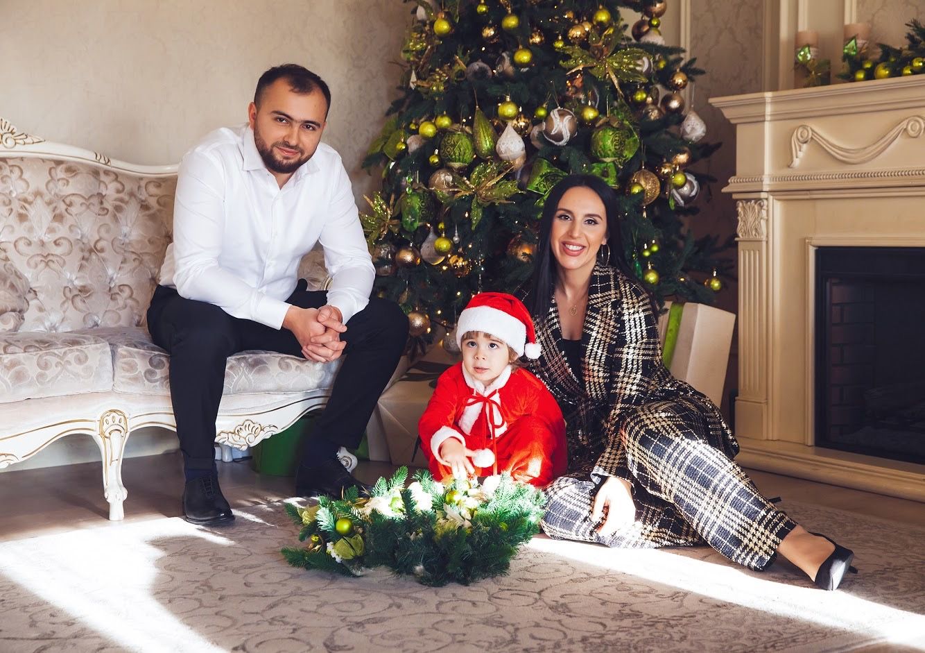 Family Christmas portrait with decorated tree and white fireplace in background.