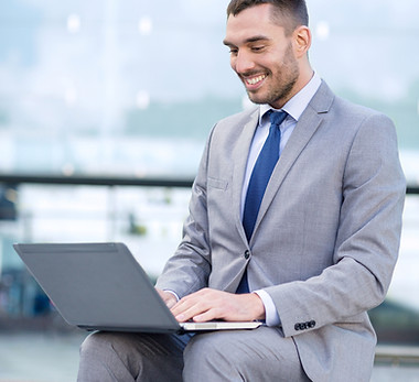 Smiling businessman in grey suit on Laptop