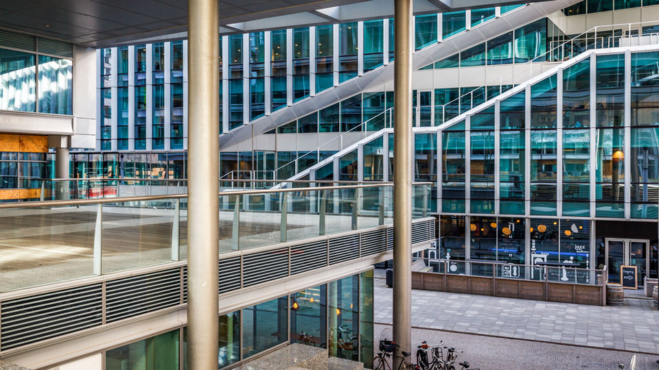 Moderne architectuur met glazen gevels, stalen balkons en spiegelende raampartijen in een stedelijke omgeving, professioneel vastgelegd door RE-Framed