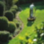 gardener-mowing-lawn-trimming-bushes-wellmaintained-garden.jpg