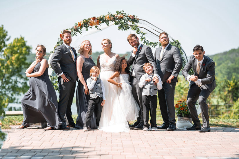 Bride and groom outdoors under archway surrounded by family and friends