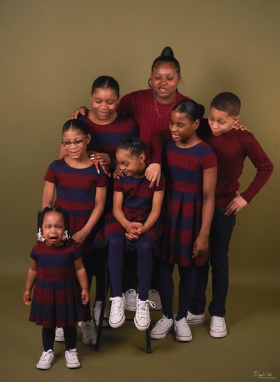 Family of 7 wearing red and black stripes looking at crying toddler
